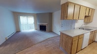 Located at 14901 SE 272nd St in Kent, Washington, this ground-floor unit offers a well-organized, single-level layout designed for comfortable everyday living. The open-concept living and dining area is anchored by a stone-surround fireplace, creating a warm focal point for the space. Large sliding glass doors lead to a private patio, allowing natural light to fill the room. The flooring transitions between smooth hardwood-style planks in the entry and kitchen areas and plush carpet throughout the living and bedroom spaces.

The galley-style kitchen is thoughtfully appointed with warm oak cabinetry extending to the ceiling for ample storage, light-toned countertops, a double sink, a dishwasher, a refrigerator, and an electric range. A peninsula with an overhang connects the kitchen to the living area, offering casual dining or prep space.

The bedrooms are carpeted and well-proportioned, with one featuring dual sliding closets for abundant storage and another offering a single closet alongside a window with natural light. A dedicated in-unit laundry closet adds everyday convenience. Baseboard heating is present throughout, ensuring consistent warmth. The unit's clean, neutral palette provides a versatile backdrop suitable for a variety of décor styles.