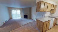 Located at 14901 SE 272nd St in Kent, Washington, this ground-floor unit offers a well-organized, single-level layout designed for comfortable everyday living. The open-concept living and dining area is anchored by a stone-surround fireplace, creating a warm focal point for the space. Large sliding glass doors lead to a private patio, allowing natural light to fill the room. The flooring transitions between smooth hardwood-style planks in the entry and kitchen areas and plush carpet throughout the living and bedroom spaces.

The galley-style kitchen is thoughtfully appointed with warm oak cabinetry extending to the ceiling for ample storage, light-toned countertops, a double sink, a dishwasher, a refrigerator, and an electric range. A peninsula with an overhang connects the kitchen to the living area, offering casual dining or prep space.

The bedrooms are carpeted and well-proportioned, with one featuring dual sliding closets for abundant storage and another offering a single closet alongside a window with natural light. A dedicated in-unit laundry closet adds everyday convenience. Baseboard heating is present throughout, ensuring consistent warmth. The unit's clean, neutral palette provides a versatile backdrop suitable for a variety of décor styles.