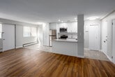 Located at 470 Scenic Dr in London, Ontario, this well-appointed 2-bedroom, 1-bathroom unit offers a thoughtfully designed single-floor layout with a clean, modern aesthetic. The open-concept kitchen and living area serves as the heart of the home, where crisp white cabinetry, a stone-look peninsula countertop, and a full suite of stainless steel appliances — including a refrigerator, stove, microwave, and dishwasher — create a functional and stylish cooking space. Recessed lighting illuminates the kitchen, while wood-look flooring flows throughout the main living areas, adding warmth and continuity. The living room benefits from natural light through roller-shaded windows with views of surrounding greenery. Both bedrooms are comfortably sized, with the spacious primary bedroom featuring a wide window arrangement that fills the room with natural light. The second bedroom also offers a pleasant window outlook with a baseboard heating unit. A hallway connects the private areas of the unit, leading to the full bathroom, which includes a tiled tub-shower combination with a chrome grab bar and showerhead. Neutral wall tones, clean white trim, and consistent wood-look flooring throughout give the unit a cohesive, move-in-ready feel.