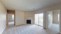 Located at Bridle Creek, this single-floor residence offers a practical and comfortable layout across several well-defined living spaces. The living room serves as the heart of the home, featuring plush wall-to-wall carpeting, a tile-surround fireplace with a white mantel, and a sliding glass door that opens to a private balcony overlooking the surrounding area, allowing natural light to fill the space. The textured ceiling and neutral wall tones throughout lend a clean, cohesive aesthetic.

The kitchen is designed for functionality, featuring white cabinetry, laminate countertops, wood-look flooring, and a full suite of white appliances including an electric range, dishwasher, and refrigerator. A bold navy accent wall adds a distinct visual contrast to the bright cabinetry.

The bedrooms are carpeted and finished in soft, neutral tones, each benefiting from windows that bring in natural light and views of surrounding greenery. One bedroom includes a walk-in closet, providing generous storage. An additional open carpeted room offers flexible use as a secondary living or dining area.

The bathroom features a vanity with ample cabinet storage, a large mirror with overhead lighting, and a functional layout. Throughout the unit, clean finishes and a neutral palette create a welcoming, move-in-ready environment.