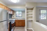 Located at 2404 Brightseat Rd in Hyattsville, MD, this single-floor unit offers a practical and comfortable layout designed to maximize every square foot. The combined kitchen and living room serves as the heart of the home, featuring warm hardwood-style flooring, a two-tone beige color scheme with a decorative chair rail, and a front entry door flanked by windows that invite natural light and outdoor views. The kitchen is well-equipped with warm-toned wooden cabinetry, stainless steel appliances including a refrigerator and gas range, a blue tile backsplash, and a peninsula counter that provides additional prep space and a natural divider from the living area. Built-in open shelving adds practical storage. The bedroom offers a comfortable retreat, complete with a large double-door closet for ample storage, hardwood-style flooring, and a window with a green outdoor view. Neutral, light walls throughout the unit create a clean, open ambiance. The consistent flooring and cohesive color palette tie the spaces together, lending the unit a unified and move-in ready feel. A covered outdoor area is also accessible, adding additional functional space to the property.