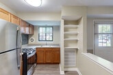 Located at 2404 Brightseat Rd in Hyattsville, MD, this single-floor unit offers a practical and comfortable layout designed to maximize every square foot. The combined kitchen and living room serves as the heart of the home, featuring warm hardwood-style flooring, a two-tone beige color scheme with a decorative chair rail, and a front entry door flanked by windows that invite natural light and outdoor views. The kitchen is well-equipped with warm-toned wooden cabinetry, stainless steel appliances including a refrigerator and gas range, a blue tile backsplash, and a peninsula counter that provides additional prep space and a natural divider from the living area. Built-in open shelving adds practical storage. The bedroom offers a comfortable retreat, complete with a large double-door closet for ample storage, hardwood-style flooring, and a window with a green outdoor view. Neutral, light walls throughout the unit create a clean, open ambiance. The consistent flooring and cohesive color palette tie the spaces together, lending the unit a unified and move-in ready feel. A covered outdoor area is also accessible, adding additional functional space to the property.