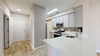 This well-appointed 3-bedroom, 2-bathroom single-floor residence at 14110 Big Crest Lane in Woodbridge, VA offers a thoughtfully designed layout with modern finishes throughout. Light-toned luxury vinyl plank flooring flows through the main living areas, complemented by neutral warm-gray walls that lend a clean, contemporary feel.

The kitchen is a standout feature, boasting gray shaker-style cabinetry, gleaming quartz countertops, a peninsula with an undermount sink, and a full suite of stainless steel appliances including a gas range, built-in microwave, dishwasher, and refrigerator. The open sightline from the kitchen connects seamlessly to the living room, which features a ceiling fan and large sliding glass doors that invite abundant natural light and outdoor views.

The generously sized primary bedroom includes sliding glass door access to the outdoors and plush carpeting, while the additional bedrooms also feature carpet and bright windows with neighborhood views. Both bathrooms are finished with granite-topped vanities, wood-look tile flooring, and tiled tub-shower combinations.

A dedicated in-unit laundry room houses a full-size washer and dryer. Three closets provide ample storage throughout. The home also includes a connecting hallway that ties the layout together efficiently, making this a comfortable and functional residence.