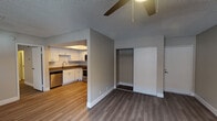 This single-floor residence offers a thoughtfully designed open-concept layout that seamlessly connects the living areas to the kitchen. The kitchen is a standout feature, showcasing crisp white shaker cabinetry, white subway tile backsplash, dark countertops, and a full suite of stainless steel appliances including a refrigerator, range, microwave, and dishwasher. A recessed tray ceiling with track lighting adds a refined touch overhead. Durable wood-look flooring flows throughout the space, tying each room together cohesively. The living area is bright and airy, benefiting from a sliding glass door that opens to an outdoor patio and an additional side window that invites natural light. Ceiling fans are present in multiple rooms, enhancing comfort throughout. The bedrooms are well-sized, each with neutral-toned walls and ample natural light; one features a sliding closet, while another offers a walk-in closet for generous storage. The bathroom is clean and functional, complete with a tub-shower combination, a modern floating-style vanity with a white countertop, and a framed mirror. Textured ceilings and clean white trim finish each space with a polished look.