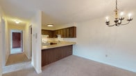 Located at 17 Conant in Beverly, Massachusetts, this single-floor residence offers a well-organized and functional layout across several distinct living areas. The kitchen is designed with dark wood cabinetry, light laminate countertops, a white electric range, a stainless steel sink, and a tiled backsplash. It opens to the main living and dining area via a peninsula counter, creating an accessible, connected feel ideal for everyday living and entertaining. A chandelier accents the dining area, adding a touch of warmth to the open space.

The living areas are finished with neutral wall-to-wall carpeting and light-toned walls, contributing to a clean, understated aesthetic throughout. Baseboard heating is present in multiple rooms, ensuring year-round comfort. The bedrooms are generously sized, with one featuring a walk-in closet alongside an additional standard closet, offering ample storage. Windows in the bedrooms provide natural light and views of the surrounding neighborhood.

The bathroom is notably spacious, equipped with accessibility-friendly grab bars near the tub and toilet, a combination tub and shower, tile flooring, and a vanity with a granite-style countertop. The overall layout is practical and move-in ready, with a straightforward design that suits a wide range of occupants.