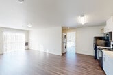 Located in Beaverton, Oregon, this single-floor, 3-bedroom, 2-bathroom home offers a practical and clean layout designed for comfortable everyday living. The interior is unified by rich wood-style flooring that runs throughout, complementing the bright white walls and creating a warm, cohesive aesthetic.

The open living area is bathed in natural light from large windows fitted with horizontal blinds, offering pleasant outdoor views of surrounding trees and the neighborhood. A convenient in-unit stacked washer and dryer is tucked neatly between the living space and an additional room, adding functional value without sacrificing flow.

The kitchen features a streamlined galley-style design with white cabinetry, open shelving, light countertops, and a full suite of black appliances including a refrigerator, electric range with over-the-range microwave, and a stainless sink — providing everything needed for efficient meal preparation.

The spacious primary bedroom offers generous proportions with a dedicated closet, while the two additional bedrooms are clean and versatile. Both bathrooms are simply finished with white surrounds, tub-shower combinations, and wood-style flooring. The overall ambiance of the home is light, neutral, and move-in ready.