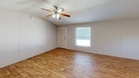 Located at 200 Logan Dr in Phenix City, Alabama, this single-floor, 3-bedroom, 2-bathroom home offers a practical and comfortable layout. The open-concept living and kitchen area is immediately welcoming, featuring warm wood-look laminate flooring, vaulted ceilings, and a ceiling fan that adds both style and function. Natural light filters in through windows, brightening the connected spaces.

The kitchen is well-appointed with white cabinetry, a stone-tile backsplash, granite-style countertops, and black appliances including a range, over-the-range microwave, and refrigerator. A double-basin sink with a window above it adds a practical touch to the space.

The three bedrooms are comfortably sized, each featuring the same wood-look flooring and ceiling fixtures. The primary bedroom offers generous proportions, while the additional bedrooms include closet space and windows for natural light.

The two bathrooms are clean and functional. One features a full tub/shower combo with white tile surround, while the other includes a vanity with dark countertop, a wall mirror with overhead lighting, and a tub/shower unit. Throughout the home, the neutral gray wall tones and consistent flooring create a cohesive, move-in-ready aesthetic.