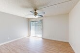 This 2-bedroom, 2-bathroom single-floor residence on West Bullard Avenue in Fresno, California offers a practical and comfortable layout. Light wood-style flooring runs throughout the main living areas, complemented by neutral-toned walls and textured ceilings. The living room is bright and open, featuring a ceiling fan with light fixture and a sliding glass door fitted with vertical blinds that allows natural light to pour in and provides outdoor access. The kitchen and dining area are combined in an efficient open-concept arrangement, with the kitchen showcasing rich wood cabinetry, a white appliance suite, and a pass-through counter that connects to the dining space. Both bedrooms are carpeted for comfort; the primary bedroom includes a sliding glass door with outdoor views, while the secondary bedroom features a window that brings in natural light. Three closets are distributed throughout the unit for ample storage. The two bathrooms are finished with wood-toned vanities, light-colored countertops, and wood-style flooring. One bathroom features a standalone shower enclosure, while the other includes a tub-shower combination with a sliding glass door. A dedicated laundry area and a connecting hallway complete the well-organized floor plan.