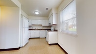 This two-floor space offers a straightforward and practical layout designed for comfortable everyday living. A carpeted staircase with clean white railings and a glass panel connects the two levels, with speckled hard-surface flooring extending through the lower common areas.

The kitchen is a functional highlight, equipped with white cabinetry, dark laminate countertops, and white appliances including a refrigerator, electric range, and dishwasher. A window above the counter area allows natural light to brighten the space and offers an outdoor view. The layout provides ample cabinet storage both above and below the counters.

The bedrooms feature neutral carpet flooring, white walls, and dark baseboards. Each room benefits from natural light through blinded windows, and several include sliding wood-panel closet doors, adding practical storage. The rooms are spacious enough to accommodate various furniture configurations.

The bathrooms are efficiently designed, each featuring a wood-toned vanity with storage below and a medicine cabinet above. One bathroom includes a walk-in shower stall with clean white surrounds and tile-style flooring. The overall ambiance throughout the space is clean, neutral, and move-in ready.