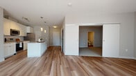 Located on Franklin Blvd in Cleveland's 44113 zip code, this single-floor unit offers a thoughtfully designed open-concept layout that blends modern finishes with functional living. The main living area is anchored by wide-plank hardwood flooring and large windows dressed with vertical blinds, allowing generous natural light to fill the space throughout the day.

The kitchen is a standout feature, equipped with crisp white shaker cabinetry extending to the ceiling, light quartz countertops, a subway tile backsplash, and a full suite of stainless steel appliances including a refrigerator, electric range, over-the-range microwave, and dishwasher. A central island with pendant lighting above provides additional counter space and serves as a natural gathering point that opens to the living area.

The bedroom is carpeted for comfort and features a spacious walk-in closet with wire shelving, offering ample storage. An en-suite bathroom presents white cabinetry, a large framed mirror, and a light countertop with modern fixtures. In-unit washer and dryer connections are also available. The neutral gray and white color palette throughout lends the space a clean, contemporary feel, making it move-in ready.