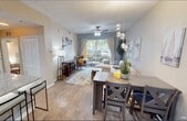 Located at 2051-2059 SE Hillmoor Dr in Port Saint Lucie, FL, this well-appointed single-floor residence offers a thoughtfully designed open-concept layout that seamlessly connects the kitchen, dining, and living areas. The kitchen is a standout feature, showcasing white shaker-style cabinetry, granite countertops, stainless steel appliances including a French door refrigerator, a deep undermount sink with a modern pull-down faucet, and a peninsula island with bar seating — ideal for casual dining or entertaining. Light wood-look flooring flows throughout the main living areas, enhancing the bright and airy atmosphere. The dining area is accented by a contemporary pendant light fixture, while the spacious living room benefits from a ceiling fan, neutral-toned walls, and large sliding glass doors that open to a private balcony, filling the space with natural light and outdoor views. The bedroom is a serene retreat, featuring a ceiling fan, soft neutral tones, and ample space for a full furniture arrangement. The bathroom continues the refined aesthetic with granite countertops, white cabinetry, a well-lit vanity mirror, and wood-look flooring. Overall, the space presents a clean, modern, and cohesive design throughout.