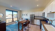 Located at 223 S Mitchell St in the heart of downtown Cadillac, Michigan, this thoughtfully designed single-floor unit offers a contemporary living experience with a clean, modern aesthetic throughout. The open-concept layout seamlessly connects the kitchen, dining, and living areas, creating an inviting and functional space filled with natural light.

The kitchen is a standout feature, equipped with stainless steel appliances including a refrigerator, range, and microwave, complemented by white shaker-style cabinetry, a classic subway tile backsplash, and dark countertops. Light hardwood-style flooring flows throughout the main living area, adding warmth and continuity to the space.

Large, black-framed windows in both the living area and bedroom flood the unit with natural light while offering elevated views of the surrounding downtown streetscape. The bedroom is a comfortable retreat, featuring exposed industrial-style ductwork at the ceiling that adds a subtle urban character to the space.

The bathroom is finished with light blue-gray walls, a white vanity with ample storage, a framed mirror, and a glass-enclosed shower, creating a clean and calming atmosphere. Overall, this unit combines modern finishes with practical design, making it a well-rounded space ideally situated in downtown Cadillac.