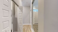 This single-floor, one-bedroom, two-bathroom residence offers a well-planned layout that balances open living areas with private spaces. The kitchen serves as a central highlight, featuring rich cherry-toned cabinetry, granite countertops, a large center island with a built-in sink, stainless steel appliances including a gas range, microwave, and French door refrigerator, and a stainless steel range hood. Light hardwood flooring runs throughout the kitchen and main living areas, complemented by crown molding and ample natural light from multiple windows.

The spacious bedroom is carpeted for comfort and includes a closet, ceiling fan, and large windows that frame urban skyline views. A second mirrored sliding door closet is also present, with a stacked washer and dryer conveniently integrated nearby.

Both bathrooms are finished to a high standard with striking horizontally-striped gray and white tile work covering the floors and walls. One bathroom features a glass-enclosed tub-shower combination, while the other boasts a large walk-in glass shower with mosaic tile flooring and a built-in shelf. A hallway connects the rooms efficiently, with light hardwood flooring continuing the cohesive aesthetic throughout the space.