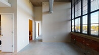 Located at 275 Winchester Ave in New Haven, CT, this industrial-modern unit masterfully blends raw architectural character with contemporary finishes. Soaring ceilings with exposed spiral ductwork and polished concrete floors throughout establish a loft-inspired aesthetic, while large, multi-pane factory-style windows flood the living areas with abundant natural light and outdoor views of the surrounding neighborhood.

The kitchen is thoughtfully designed with rich wood-grain cabinetry, white quartz countertops, a tile backsplash, and a full suite of stainless steel appliances including a range, over-the-range microwave, dishwasher, and refrigerator. The U-shaped layout maximizes counter and storage space.

Two well-appointed bathrooms serve the unit — one features a sleek walk-in shower with white subway tile and a floating vanity with quartz countertop, while the second offers a full soaking tub with matching subway tile surround and vanity. Both bathrooms continue the polished concrete flooring found throughout the space.

Generous walk-in closet space provides ample storage with wire shelving systems. The entry area includes a discreet in-unit washer, adding everyday convenience. Exposed concrete columns and original brick accents at the window sills further reinforce the building's industrial heritage, creating a distinctive and characterful living environment.