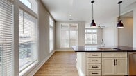 This contemporary apartment offers a harmonious blend of comfort and style across its 1100 square feet. The heart of the home is an expansive open-concept area, combining the kitchen and living room for a seamless flow. Large windows dominate one wall, flooding the space with natural light and providing a connection to the outdoors. The floors feature light-toned wood-look material, enhancing the bright and airy atmosphere.

The primary bedroom, generously sized at 180 square feet, promises a peaceful retreat. Both bedrooms are complemented by their own closets, ensuring ample storage. The two full bathrooms add convenience and privacy for residents and guests alike.

A notable feature is the glass door leading to a private balcony or patio, perfect for enjoying fresh air or al fresco dining. The room's ceiling fan adds both style and functionality. Crisp white walls and trim create a clean canvas, allowing for personalization of the space.

A hallway connects the various rooms, maintaining an efficient layout. The overall design emphasizes a modern, minimalist aesthetic with a focus on maximizing light and space, creating an inviting and versatile living environment.
