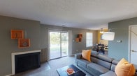Located at 3451 Sherburne Ln in Indianapolis, Indiana, this single-floor residence offers a well-organized layout with distinct living, dining, kitchen, and bedroom spaces. The living room serves as the heart of the home, featuring a tiled fireplace, built-in wall shelving, and large sliding glass doors that open to outdoor views of a scenic waterfront. Neutral carpet and textured ceilings carry throughout the main living areas, contributing to a warm and cohesive atmosphere. Adjacent to the living room, the dining area benefits from natural light streaming through multiple windows and is topped by a ceiling fan, with direct access to the galley-style kitchen. The kitchen is outfitted with dark wood cabinetry on both sides, a double stainless steel sink, and light tile flooring, providing practical and efficient use of space. The primary bedroom is spacious and carpeted, featuring ample natural light and a walk-in closet with built-in shelving. A secondary bedroom includes a large window with outdoor views and a bi-fold closet. The bathroom is complete with a vanity, mirror, and shower-tub combination. A welcoming entryway with carpeted flooring connects the living spaces, rounding out this functional and comfortable single-level home.