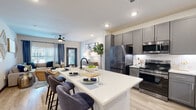 Located at 21447 FM-529 in Katy, TX, this single-story residence offers a thoughtfully designed open-concept layout that seamlessly connects the kitchen, dining, and living areas. The kitchen is a standout feature, showcasing floor-to-ceiling gray shaker cabinetry, a classic white subway tile backsplash, stainless steel appliances including a French door refrigerator and electric range, and a generous central island with a white quartz countertop and bar seating for three — ideal for casual dining and entertaining. Light wood-style flooring flows throughout, enhancing the bright and airy atmosphere created by recessed lighting and multiple windows. The living area is a comfortable retreat, highlighted by a ceiling fan, large windows with decorative drapes, and ample space for relaxing. The bedroom is well-appointed with large windows that invite natural light and outdoor views, along with access to a walk-in closet. The bathroom features gray cabinetry with a white countertop vanity, a tub-shower combination, and wood-look tile flooring, maintaining the cohesive modern aesthetic found throughout the unit. The front entry, framed by a bold gray door, adds a polished finishing touch to this well-designed Katy-area residence.