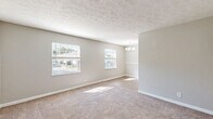 Located at 1512 E 10th St in Jeffersonville, Indiana, this one-bedroom, one-bathroom unit offers a practical and comfortable single-floor layout. The living area features neutral gray walls and plush wall-to-wall carpeting, creating a warm and inviting atmosphere with easy access to the kitchen. The kitchen is efficiently designed with white cabinetry, granite-look countertops, a stainless steel electric range, and black refrigerator, all set atop wood-look vinyl flooring. A skylight-style ceiling fixture brightens the galley-style space. The hallway connects the rooms seamlessly, maintaining a logical and functional flow throughout. The bedroom is a well-proportioned retreat with soft carpeting, a textured ceiling, and a window that allows natural light and outdoor views to fill the room. The bathroom is tastefully finished with wood-look flooring, a white vanity topped with granite countertops, a large mirror with stylish lighting, and a full tub/shower combo. Grab bars are conveniently installed, adding a practical safety feature. Throughout the unit, consistent gray tones and clean white trim create a cohesive, modern aesthetic that is both understated and welcoming.