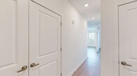 This contemporary single-floor space is thoughtfully designed with a clean, modern aesthetic carried consistently throughout. Light hardwood-style flooring runs seamlessly across all areas, complementing the crisp white walls and creating a bright, cohesive feel.

The kitchen serves as a central highlight, showcasing a large island with a granite countertop, undermount sink, and stylish pendant lighting overhead. Cabinetry combines white upper cabinets with dark wood lower cabinets, paired with a white subway tile backsplash. Stainless steel appliances, including a refrigerator, range, and built-in microwave, complete the well-appointed space.

The living and dining areas benefit from generous natural light streaming through multiple oversized windows fitted with horizontal blinds, offering elevated views of the surrounding neighborhood. A glass-paned exterior door further enhances connectivity to the outdoors.

The bedrooms are well-proportioned and airy, each featuring large windows that frame outdoor views, with one room including a ceiling fan. Recessed lighting is present throughout the unit, ensuring consistent illumination.

The bathroom is finished with a granite-topped dark wood vanity, a soaking tub with shower combination, and light flooring that mirrors the rest of the unit. A hallway with recessed lighting and paneled doors connects the various spaces, reinforcing the unit's clean, functional layout.