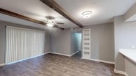 This single-floor residence combines modern updates with warm, characterful design elements throughout. The spacious living area serves as the centerpiece of the home, featuring distinctive exposed rustic wood ceiling beams that add architectural interest and contrast beautifully against the neutral gray walls. A ceiling fan, flush-mount lighting, and vertical blinds covering a sliding door complete the living space, which also benefits from a set of built-in wall shelves—ideal for display or storage. Durable hardwood-style flooring flows consistently throughout the home, contributing to a cohesive and easy-to-maintain aesthetic.

The kitchen is thoughtfully designed with crisp white shaker-style cabinetry, light quartz countertops, a stainless steel undermount sink, and stainless steel appliances including an over-the-range microwave and dishwasher. A window above the counter brings in natural light, enhancing the clean, contemporary feel.

The bedrooms are generously sized, each equipped with a ceiling fan and vertical blinds or window treatments for light control and privacy. The bathrooms are neatly appointed, featuring white vanities with framed mirrors and a tub-shower combination with elegant marble-style tile surround. One bathroom includes a separate vanity area, adding practical functionality to the layout.