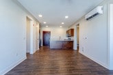 Located at 6743 W 135th St in Overland Park, Kansas, this single-floor unit offers a thoughtfully designed layout with consistent, high-quality finishes throughout. Rich wood-look tile flooring runs through the main living areas and bathrooms, creating a warm, cohesive aesthetic. The open-concept living area features crown molding, recessed lighting, a ceiling fan, and a wall-mounted mini-split HVAC unit. A sliding glass door leads to a private balcony, offering views of the surrounding landscape. The kitchen is centrally positioned and equipped with rich walnut-toned cabinetry, granite countertops, stainless steel appliances including a range, microwave, and dishwasher, and a peninsula with an undermount sink. A walk-in pantry with built-in shelving provides generous storage. The bedrooms are carpeted for comfort, with large windows that invite natural light and views of the outdoors, plus individual ceiling fans and wall-mounted mini-split units for climate control. The primary bathroom is elegantly appointed with a vessel sink atop a granite-topped dark wood vanity, an illuminated frameless mirror, and wood-look tile flooring, leading to a walk-in closet with multi-tier shelving and hanging rods. A second bathroom features a sliding glass-enclosed shower with decorative mosaic tile accents. The overall ambiance is clean, modern, and move-in ready.
