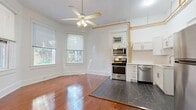 Located at 656 Beach Dr NE in the heart of Saint Petersburg, Florida, this efficiently designed single-floor unit offers a bright and functional layout. The main living area features warm, richly toned hardwood floors that contrast beautifully with the crisp white walls, creating a clean and inviting atmosphere. Multiple windows allow natural light to fill the space, while a ceiling fan provides year-round comfort. Exposed copper piping running along the upper walls adds a distinctive industrial character to the interior.

The kitchen is seamlessly integrated into the living area and transitions to dark slate-style tile flooring. It is equipped with stainless steel appliances, including a gas range with oven, microwave, dishwasher, and full-size refrigerator, all complemented by white shaker-style cabinetry and a functional sink. A wall-mounted air conditioning unit serves the space.

The bathroom continues the dark tile flooring seen in the kitchen and includes a white vanity with under-cabinet storage, open wall shelving, a bathtub, and a mirror above the sink. A dedicated closet provides additional storage. The overall aesthetic is clean and utilitarian, with a mix of classic and modern elements that make this a practical and characterful space in one of Florida's most vibrant coastal cities.