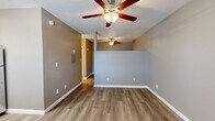 Located at 4250 E 29th St in Tucson, Arizona, this single-floor unit offers a clean, updated living environment with a cohesive neutral color palette throughout. Wood-look luxury vinyl plank flooring runs continuously across the living, sleeping, and hallway areas, providing a warm and durable foundation underfoot. Ceiling fans are installed in multiple rooms, an important comfort feature well-suited to the Tucson climate.

The open layout connects the main living area to the kitchen, which is equipped with white cabinetry and a stainless steel refrigerator. A wall-unit air conditioner near the front entry provides additional climate control. The front door area also features a window with blinds, allowing natural light into the entryway.

A hallway leads to the bathroom, which stands out as a notably upgraded space. It features a dual-sink vanity topped with granite countertops, white shaker-style cabinets, and Hollywood-style vanity lighting above dual mirrors. An adjoining wet area showcases a full tub and shower combination clad in large-format marble-look tile, creating a polished, contemporary aesthetic.

Throughout the unit, textured ceilings and clean white baseboards complement the neutral taupe and gray wall tones, resulting in a cohesive, move-in ready interior.