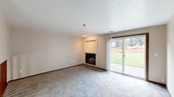 Located in Vancouver, Washington, this two-story home offers a practical and comfortable layout across two floors. The main level features a carpeted living room centered around a built-in electric fireplace with a display shelf above, creating a warm and inviting focal point. The kitchen is equipped with rich oak cabinetry, light granite-style countertops, a double stainless steel sink beneath a window, and includes a range and built-in microwave. Three bathrooms serve the home, including one with wood-toned vanity cabinetry, a tub/shower combo, and light wood-look tile flooring. The upper level houses the bedrooms, including a generously sized primary bedroom with mirrored sliding closet doors and an adjacent bathroom. The second bedroom features a large window with views of surrounding greenery, filling the space with natural light and soft carpeting underfoot. Staircases with warm wood railings connect the two floors. Additional highlights include an attached garage with an automatic opener, exposed wood-truss ceiling, and direct interior access. A balcony adds outdoor living options, rounding out a well-structured and functional home.