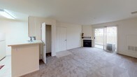 This single-floor, one-bedroom, one-bathroom residence offers a thoughtfully organized layout designed for comfortable everyday living. The main living area is spacious and carpeted, bathed in natural light from a large sliding glass door that opens to a private balcony with outdoor views. A fireplace serves as a focal point along the main wall, adding warmth and character to the room. A ceiling fan overhead contributes to the room's airflow and comfort.

The kitchen is efficiently designed in a galley style, featuring light wood cabinetry, ample upper and lower cabinet storage, white appliances including a range, microwave, and refrigerator, and light-toned flooring. A peninsula counter with a sink connects the kitchen to the living area, creating an open and functional flow between the two spaces.

The bedroom is a quiet, carpeted retreat with a large window dressed in vertical blinds that allow natural light while maintaining privacy, with greenery visible outside. A mirrored sliding closet adds practicality and visual depth to the room.

The bathroom is cleanly finished with tile flooring and features a tub/shower combination with a curtain rod, along with accessibility-friendly grab bars installed near the toilet and shower area. Throughout the residence, neutral tones and clean finishes create a calm, move-in-ready atmosphere.