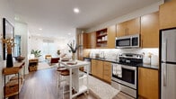 Located at 610 Sylvan Heights Way in Nashville, TN, this single-floor residence offers a thoughtfully designed layout that blends modern style with everyday functionality. The open-concept kitchen is a standout feature, outfitted with warm honey-toned cabinetry, dark granite countertops, a white subway tile backsplash, and a full suite of stainless steel appliances including a refrigerator, range, microwave, and dishwasher. Wood-look flooring ties the kitchen seamlessly into the adjacent living area, which is bathed in natural light from large sliding glass doors. The living room offers a welcoming atmosphere with clean white walls, recessed lighting, and generous space for comfortable furnishings. The bedroom is a calm retreat, highlighted by a botanical-patterned accent wall, soft carpeting, and a window with natural light and outdoor views. The bathroom features warm wood cabinetry, dark granite countertops, a large vanity mirror with sconce lighting, and clean tile flooring. Throughout the unit, the design reflects a cohesive modern aesthetic, combining neutral tones, quality finishes, and practical storage solutions that make this Nashville residence both stylish and highly livable.
