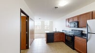 This well-designed 1-bedroom, 1-bathroom unit makes efficient use of its single-floor layout, offering a cohesive and functional living environment. The open-concept kitchen flows naturally into the living area, creating a seamless and connected space. The kitchen is outfitted with warm-toned wooden cabinetry, dark granite countertops, and a full suite of black appliances including an electric range, over-the-range microwave, dishwasher, and a stainless steel refrigerator. A peninsula counter with a built-in sink serves as a natural divider between the kitchen and the carpeted living area, which is brightened by a pair of windows offering views of the surrounding neighborhood. The bedroom is a cozy, carpeted retreat featuring a large multi-pane window that invites generous natural light and urban views, along with access to a dedicated closet. The bathroom is finished with tile flooring and includes a walk-in shower and standard fixtures in a clean, minimal design. A private entrance with a sliding closet panel completes the unit. Tile flooring carries through the kitchen, entrance, and bathroom, while soft carpet adds comfort to the living and sleeping areas.
