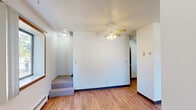 Located at 2333 Long Ave in Saint Paul, MN, this multi-floor home spans three levels and offers a practical, functional layout. The main living level features an open kitchen and living room area, where warm honey-toned wood cabinetry, light countertops, and a double sink create a welcoming and efficient kitchen space. The living room is bright and open, with light hardwood flooring, multiple windows that invite natural light, a ceiling fan, and a wall-mounted air conditioning unit. Both bedrooms are carpeted and feature baseboard heating, textured ceilings, and generous closet space with sliding or standard doors. The primary bedroom is notably spacious, with large windows offering outdoor views. The full bathroom includes a single-sink vanity with white cabinetry, a large mirror, and a tub/shower combination, all set on light hardwood floors. A central staircase connects the floors, with a wooden staircase leading down to the unfinished basement — a wide-open space with painted concrete floors and block walls, offering abundant storage or conversion potential. Baseboard heating is consistent throughout the home, providing reliable warmth suited to Minnesota's climate.