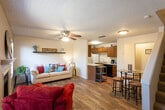 Located at 5411 Fourth St in Lubbock, Texas, this two-story residence offers a practical and inviting layout across two floors. The main level features wood-look flooring throughout, creating a warm and cohesive aesthetic. The open-concept living and dining area is bright and welcoming, with a ceiling fan, a decorative wall shelf, and windows fitted with blinds that allow for natural light control. A fireplace adds character to the living space, while a staircase leads to the upper level. The kitchen is efficiently designed with warm wood cabinetry, a peninsula countertop, a built-in dishwasher, a refrigerator, and a sink — all complemented by a textured ceiling finish consistent throughout the home. A portable utility cart provides additional prep or storage space. The dining area accommodates a glass-top bistro table with bar-height stools, ideal for casual meals. Upstairs, the bedroom features plush carpeting, a ceiling fan, and a window with natural light, offering a comfortable and private retreat. Overall, this home combines functional design with cozy details, making it a well-rounded space suited for everyday living in Lubbock.