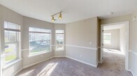 This single-floor residence at The Point at Pine Ridge in Coram, New York offers a well-designed layout with a seamless flow between living spaces. The expansive living and dining area is finished with soft, plush carpeting and neutral-toned walls, creating a bright and welcoming atmosphere. Large windows allow generous natural light to fill the space, with views of the surrounding greenery and community grounds.

The kitchen is equipped with ample white cabinetry, a gas range, an over-the-range microwave, and light-toned countertops with a tile backsplash, providing a clean and functional workspace.

The bedrooms are generously proportioned, each featuring wall-to-wall carpeting, neutral painted walls, and large windows that invite natural light and outdoor views. One bedroom includes a walk-in closet, adding practical storage.

The primary bathroom features a dual-sink vanity with white cabinetry, tile flooring, a well-lit mirror, and a separate closet area. A second full bathroom provides a single-sink vanity, tile flooring, a toilet, and a shower/tub combination, maintaining a consistent clean aesthetic throughout.

Overall, the residence presents a comfortable and functional living environment with a cohesive neutral palette, plentiful natural light, and thoughtful use of space throughout every room.