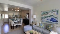 Spanning three floors, this thoughtfully designed space offers a seamless blend of comfort and style. The open-concept main living area draws the eye with a spacious living room featuring a ceiling fan, soft neutral walls, and vibrant artwork that adds a splash of color and personality. A plush sofa, accent ottoman, and natural wood coffee table create a welcoming gathering space. An arched passageway connects the living area to a refined dining room, where an elegant chandelier illuminates a generously sized dining table surrounded by upholstered chairs — perfect for entertaining. The kitchen beyond is well-equipped with modern stainless steel appliances, white cabinetry with glass-front accents, and ample counter space, making it both functional and visually appealing. The open flow between these spaces promotes a sense of connectivity and ease of movement throughout the main level. Subtle tile flooring runs throughout, adding a clean, cohesive aesthetic. The textured ceilings and layered lighting contribute to a warm, livable ambiance. With three floors of living space, this property offers generous room to accommodate a variety of lifestyle needs across its full footprint.