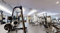 Located at 153 Valley St in South Orange, NJ, this single-floor fitness facility offers a thoughtfully designed and generously sized space dedicated entirely to health and wellness. The layout is divided into two distinct functional zones, each catering to different workout disciplines.

The main exercise room features durable rubber flooring throughout and is lined with large mirrors that enhance the sense of space. It is outfitted with an extensive array of strength and cardio equipment, including cable machines, a Smith machine, weight benches, a full dumbbell rack, treadmills, and an elliptical trainer. Overhead, recessed and linear lighting ensures a bright, energizing atmosphere, while large glass doors offer views of and access to an outdoor patio area surrounded by greenery.

The adjacent movement studio features warm hardwood flooring and floor-to-ceiling mirrors along the walls, creating an open, airy environment ideal for yoga, stretching, or group fitness. This area is equipped with stability balls, medicine balls, exercise mats, and wall-mounted punching bags. A wall-mounted flat-screen TV adds versatility to the space. Double glass doors open directly to the outdoor terrace, allowing natural light to flood the interior and connecting users to the lush outdoor surroundings. The facility is climate-controlled throughout, ensuring year-round comfort.