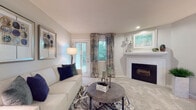 Located at 259 Lake Ridge Dr in Kalamazoo, Michigan, this single-floor residence offers a thoughtfully designed layout with comfortable living spaces and modern finishes throughout. The living room serves as a welcoming focal point, anchored by a classic white-framed fireplace and outfitted with plush carpeting, recessed lighting, and large windows dressed with decorative curtains that invite an abundance of natural light. A sliding glass door provides direct outdoor access, enhancing the sense of openness. The kitchen is efficiently designed with crisp white cabinetry, black appliances including a range, microwave, and refrigerator, and a peninsula with bar seating that seamlessly connects to a casual dining area. Light-toned flooring in the kitchen contrasts pleasantly with the soft carpet of the adjoining living spaces. The bedroom is generously sized, featuring dual windows with lush greenery views, soft carpeting, and a well-organized walk-in closet with built-in shelving. The neutral gray palette used throughout the home creates a calm, cohesive ambiance, while consistent use of blue accents in the décor ties each space together. Overall, this single-floor home presents a comfortable, move-in-ready environment with functional layouts and inviting design details.