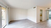 Located at 2035 Kings Hwy in Clearwater, Florida, this single-story, one-bedroom, one-bathroom unit offers a clean and functional layout designed for comfortable everyday living. The open combined living and dining area is the heart of the home, finished with light gray wood-look flooring that extends throughout much of the space. A sliding glass door floods the room with natural light and provides direct views of the surrounding outdoor grounds. The galley-style kitchen runs along a single corridor, featuring white cabinetry, a warm-toned countertop with an integrated sink, a skylight panel overhead, and white appliances including a refrigerator and range. The bedroom is a well-proportioned retreat finished with plush carpet, a window with outdoor greenery views, and generous closet storage provided by two louvered double-door closets. The full bathroom includes a tiled tub-shower combination, a vanity with countertop and mirror, and light flooring that ties the space together. Crisp white walls throughout the unit create a bright, neutral palette that is easy to personalize. The unit's efficient single-floor design ensures a smooth, accessible flow between all rooms.