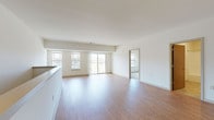 This single-floor residence is designed with a clean, contemporary aesthetic that emphasizes open space and natural light throughout. The main living area is generously proportioned, featuring smooth hardwood-style flooring that extends seamlessly from the kitchen through the living space. Large windows and a sliding glass door lead to a private balcony, flooding the interior with abundant daylight and providing views of the surrounding environment.

The kitchen is a standout feature, anchored by a large island with a granite countertop and an undermount sink. Rich, dark-stained cabinetry pairs with stainless steel appliances—including a refrigerator, range, and built-in microwave—while pendant and track lighting overhead completes the modern look. Granite countertops continue along the perimeter cabinetry, maintaining a cohesive and polished finish.

The bedrooms are carpeted for comfort and each features a well-sized window offering serene, open green landscape views. Closets with warm wood-toned doors provide practical storage. The bathroom is finished with large-format tile flooring, a granite-topped vanity with matching dark cabinetry, and a full tub-shower combination, creating a consistent and refined design language found throughout the entire space.