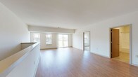This single-floor residence is designed with a clean, contemporary aesthetic that emphasizes open space and natural light throughout. The main living area is generously proportioned, featuring smooth hardwood-style flooring that extends seamlessly from the kitchen through the living space. Large windows and a sliding glass door lead to a private balcony, flooding the interior with abundant daylight and providing views of the surrounding environment.

The kitchen is a standout feature, anchored by a large island with a granite countertop and an undermount sink. Rich, dark-stained cabinetry pairs with stainless steel appliances—including a refrigerator, range, and built-in microwave—while pendant and track lighting overhead completes the modern look. Granite countertops continue along the perimeter cabinetry, maintaining a cohesive and polished finish.

The bedrooms are carpeted for comfort and each features a well-sized window offering serene, open green landscape views. Closets with warm wood-toned doors provide practical storage. The bathroom is finished with large-format tile flooring, a granite-topped vanity with matching dark cabinetry, and a full tub-shower combination, creating a consistent and refined design language found throughout the entire space.