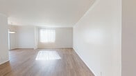 Located at 467 N Arnaz Dr in the heart of Los Angeles, CA, this single-floor unit offers a bright and clean living environment with a thoughtfully laid-out floor plan. The main living area is expansive and airy, showcasing wood-style laminate flooring, crisp white walls, and elegant crown molding that runs throughout. Large windows dressed with vertical blinds allow generous natural light to pour in, casting warm patterns across the floors. A dedicated dining area is highlighted by a classic bowl pendant light fixture and additional window access, creating a welcoming space for everyday meals. The kitchen is efficiently designed with light wood cabinetry, granite-style countertops, tile flooring, recessed lighting, and white appliances including a gas range and full-size refrigerator. The bedroom is comfortably sized, featuring plush wall-to-wall carpeting and a bright window with views of surrounding greenery. The bathrooms are well-appointed, each featuring white vanity cabinetry, warm wood-toned countertops, large mirrors, and tile flooring. The en-suite bathroom offers direct access to the bedroom, adding a practical and cohesive layout. Overall, the unit presents a clean, light-filled atmosphere ideal for comfortable urban living in a prime Los Angeles location.