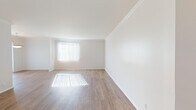 Located at 467 N Arnaz Dr in the heart of Los Angeles, CA, this single-floor unit offers a bright and clean living environment with a thoughtfully laid-out floor plan. The main living area is expansive and airy, showcasing wood-style laminate flooring, crisp white walls, and elegant crown molding that runs throughout. Large windows dressed with vertical blinds allow generous natural light to pour in, casting warm patterns across the floors. A dedicated dining area is highlighted by a classic bowl pendant light fixture and additional window access, creating a welcoming space for everyday meals. The kitchen is efficiently designed with light wood cabinetry, granite-style countertops, tile flooring, recessed lighting, and white appliances including a gas range and full-size refrigerator. The bedroom is comfortably sized, featuring plush wall-to-wall carpeting and a bright window with views of surrounding greenery. The bathrooms are well-appointed, each featuring white vanity cabinetry, warm wood-toned countertops, large mirrors, and tile flooring. The en-suite bathroom offers direct access to the bedroom, adding a practical and cohesive layout. Overall, the unit presents a clean, light-filled atmosphere ideal for comfortable urban living in a prime Los Angeles location.