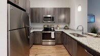 Located at Quarry Hills Drive in Quincy, Massachusetts, this single-floor residence offers a thoughtfully designed layout that balances modern aesthetics with everyday functionality. The welcoming entryway features warm hardwood-style flooring that flows seamlessly into the open-concept kitchen and living areas. The kitchen is outfitted with sleek dark wood cabinetry, granite countertops, and a full suite of stainless steel appliances, including a refrigerator, range, and over-the-range microwave — ideal for both everyday cooking and entertaining. The living room is a bright, inviting space accented by cool gray walls, natural light from a large window with sheer curtains, and rich hardwood-style flooring that adds warmth to the room. The bedroom is generously proportioned, featuring plush carpeting, a large window with teal drapes that allows ample natural light and neighborhood views, and direct access to adjacent rooms. The full bathroom is tastefully finished with tile flooring, a tub-shower combination, a vanity with dark wood cabinetry, and a cool blue-gray accent wall. Throughout the residence, a cohesive contemporary design palette of neutral tones, warm wood finishes, and thoughtful detailing creates a comfortable and stylish living environment.