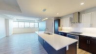 Located on Steele Street in Denver, CO, this single-floor unit offers a thoughtfully designed open-concept layout with contemporary finishes throughout. The kitchen serves as a central highlight, anchored by a large island with a white quartz countertop, undermount sink, and a bold navy base. Dark lower cabinetry contrasts with white upper cabinets, complemented by a subway tile backsplash, stainless steel appliances, a wall-mounted range hood, and pendant lighting overhead. Light wood-look flooring flows seamlessly from the kitchen into the adjacent living area, where floor-to-ceiling windows frame expansive views of the Denver skyline and surrounding cityscape, flooding the space with natural light.

The bedrooms are carpeted for comfort, each equipped with ceiling fans and closet space. The primary suite includes a generous walk-in closet outfitted with dark wood shelving and organized storage systems. Both bathrooms feature large-format tile flooring, soaking tubs with tiled surrounds accented by decorative mosaic borders, and dark-cabinetry vanities. The overall aesthetic is clean and modern, combining neutral tones with bold contrasts throughout.
