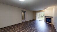 This single-floor residence offers a thoughtfully designed layout that balances open communal spaces with comfortable private areas. The living room serves as the heart of the home, featuring rich dark hardwood-style flooring, a classic fireplace, and a sliding glass door with vertical blinds that floods the space with natural light and provides access to a lush outdoor area. Track lighting accents the ceiling, and an open sightline connects the living area to the kitchen, which is outfitted with dark espresso cabinetry, a subway tile backsplash, stainless steel appliances including a range, microwave, and refrigerator, and warm wood-tone flooring. A pendant light over the kitchen counter adds a modern finishing touch. The bedrooms are carpeted for comfort, each offering a quiet retreat. One bedroom features a ceiling fan with a light fixture and a window with outdoor views, while another includes access to a walk-in closet. The bathrooms are finished with wood-look tile flooring, soaking tubs with tiled surrounds, and brushed nickel hardware and fixtures. Baseboard heating is present throughout the private areas of the home, ensuring year-round comfort. The overall aesthetic is clean, neutral, and move-in ready.
