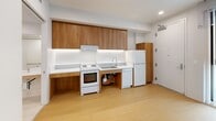 Located at 1441 W 3rd St in the heart of Los Angeles, this efficiently designed one-bedroom, one-bathroom unit offers a thoughtful layout across a single floor. Light wood flooring runs throughout, creating a warm, cohesive feel that ties each room together.

The kitchen is a functional standout, featuring warm wood cabinetry with ample upper and lower storage, white countertops with under-cabinet lighting, and a full suite of white appliances including a range, oven, sink, and refrigerator. Recessed lighting keeps the space bright and practical.

The bedroom offers a comfortable footprint with sliding closet doors providing generous storage. Recessed lighting and clean white walls give the room a simple, modern aesthetic, while the layout accommodates a variety of furniture arrangements.

The bathroom is designed with accessibility in mind, featuring stainless steel grab bars throughout, a roll-in shower with a curtain enclosure, white tile flooring, and a clean, open layout that prioritizes ease of use.

A hallway connects the rooms efficiently, and the balcony provides an outdoor retreat. Throughout the unit, the design emphasizes clean lines, neutral tones, and practical finishes — well-suited for those seeking a straightforward, move-in-ready space in central Los Angeles.