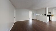 Located at 680 Evergreen Ln in Port Hueneme, California, this single-story, two-bedroom, one-bathroom home offers a clean, functional layout with consistent neutral tones throughout. The open living area features rich, dark hardwood flooring and textured ceilings, creating a warm yet understated atmosphere. Large windows with blinds allow generous natural light to fill the space, with greenery visible from outside adding a pleasant outdoor connection.

The galley-style kitchen is efficiently designed with ample white cabinetry on both sides, gray laminate countertops, a black electric range with overhead ventilation, and a stainless steel sink. A pass-through bar connects the kitchen to the living area, enhancing the open feel. A ceiling fan in the dining area promotes comfort and airflow.

Both bedrooms feature light wood-look flooring, soft gray walls, and windows with natural light. The primary bedroom includes mirrored sliding closet doors, while additional closet spaces are distributed throughout the unit. A hallway connects the private areas of the home seamlessly.

The bathroom is bright and clean, finished in white tile with a tub/shower combo and a window for natural ventilation. With three closets total, the home offers practical storage solutions throughout its well-organized floor plan.
