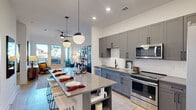 Located on 14th Street South in Birmingham's 35233 corridor, this one-bedroom, one-bathroom residence offers a thoughtfully designed single-floor layout with modern finishes throughout. The open-concept kitchen and living area forms the heart of the home, where gray shaker-style cabinetry, a white subway tile backsplash, quartz countertops, and a full suite of stainless steel appliances create a sleek, functional kitchen. A large island with seating serves as both a dining and gathering hub, illuminated by stylish globe pendant lights. Light wood-style flooring runs throughout the main living areas, complementing the bright, white walls and recessed lighting. The living room is generously proportioned, featuring large windows and a patio door that fill the space with natural light and provide outdoor access. The bedroom offers a comfortable footprint with a window framing exterior views and plush carpeting underfoot. The bathroom is finished with a dual-sink vanity in matching gray cabinetry, quartz countertops, black fixtures, a large mirror, and a glass-enclosed shower with marble-style tile surround. Additional highlights include two closets, a dedicated laundry area, and a private patio — making this a well-rounded, move-in-ready residence in Birmingham.