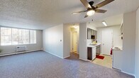 Located at 1001 Westmoreland Rd in Colorado Springs, CO, this 1-bedroom, 1-bathroom unit offers a practical and efficiently designed single-floor layout. The open living area features plush carpet flooring, a ceiling fan with integrated lighting, a textured ceiling, and a baseboard heating system. A large window with vertical blinds allows natural light to fill the space. The galley-style kitchen is thoughtfully arranged with dark wood cabinetry on both sides, white appliances including an electric range and dishwasher, a stainless steel sink with ample counter space, and tile flooring. Overhead fluorescent lighting keeps the kitchen bright and functional. The bedroom is a well-proportioned, carpeted retreat equipped with a ceiling fan, a window for natural light, and access to two closets providing convenient storage. The bathroom features a wide vanity with a white countertop, an undermount sink, and a large mirror with overhead lighting, lending a clean and practical feel. Neutral tones throughout the unit create a cohesive, understated aesthetic. The space offers a comfortable and efficient living environment suited for those seeking a manageable, move-in-ready home in Colorado Springs.