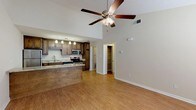Located at 2716 Dawson Rd in Albany, Georgia, this single-floor home offers a thoughtfully designed open-concept layout that seamlessly connects the living area and kitchen. The main living space features striking vaulted ceilings that amplify the sense of openness, complemented by wood-look flooring and a ceiling fan with integrated lighting. The kitchen is a standout feature, outfitted with rich dark wood cabinetry, granite-style countertops, and a full suite of stainless steel appliances including a range, over-the-range microwave, dishwasher, and refrigerator. Pendant lighting illuminates the workspace, and a peninsula counter provides additional prep space and a casual dining option. A large walk-in pantry or storage closet is conveniently accessible from the main living area. The bedroom offers a comfortable, carpeted retreat with natural light filtering through a window fitted with blinds, and a ceiling fan for year-round comfort. The bathroom is clean and functional, featuring a dark wood vanity with granite-style countertops, a tub-shower combination, and wood-look tile flooring. Throughout the home, neutral tones and consistent finishes create a cohesive and inviting atmosphere.